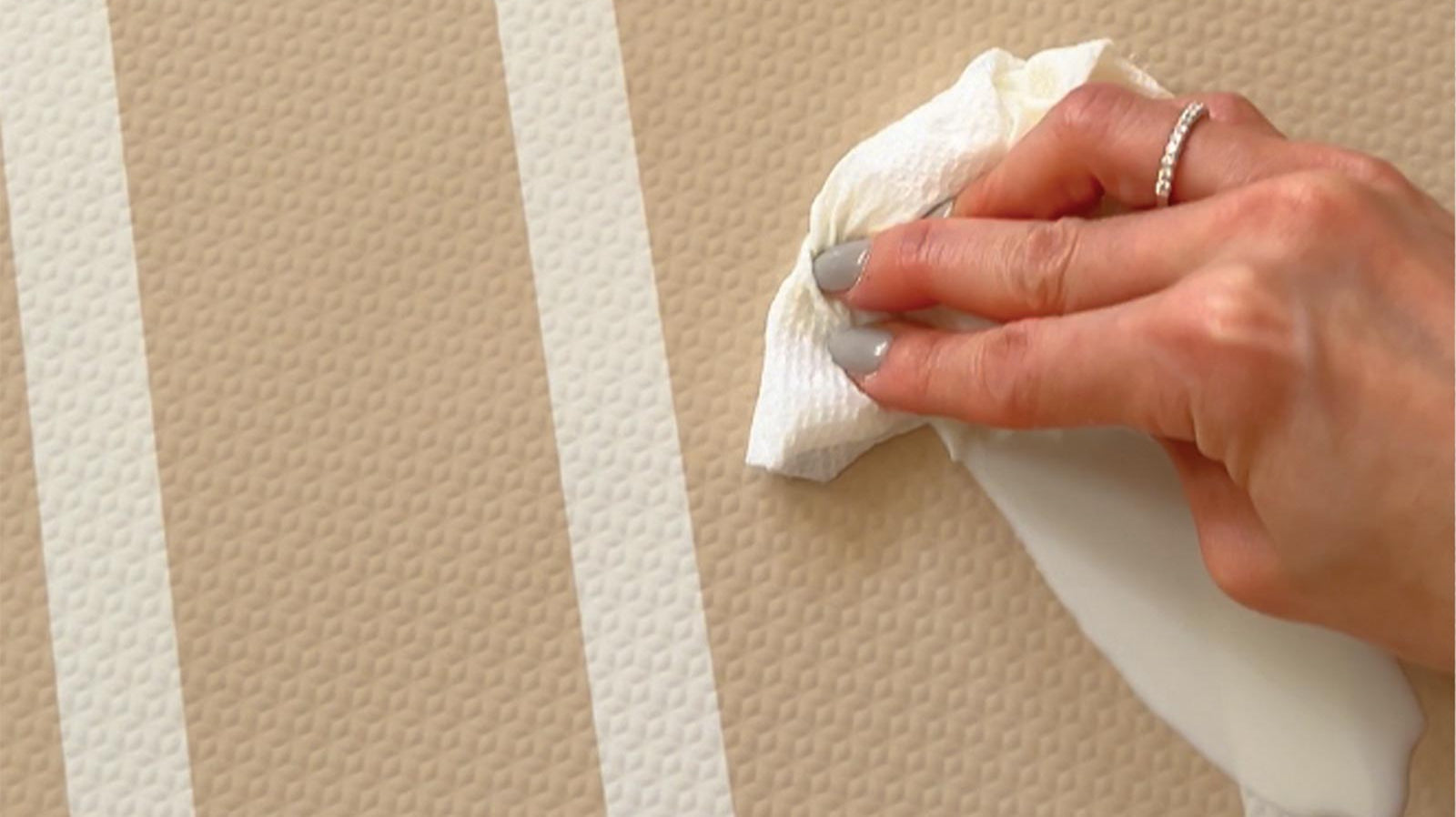 Eeveve Modern Blocks Desert Sand play mat being wiped clean after a small spill, showing its water-resistant surface.