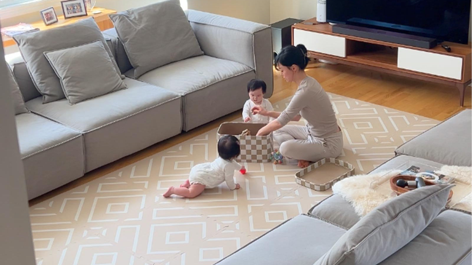Mother playing with her two children on an Eeveve play mat in the living room.