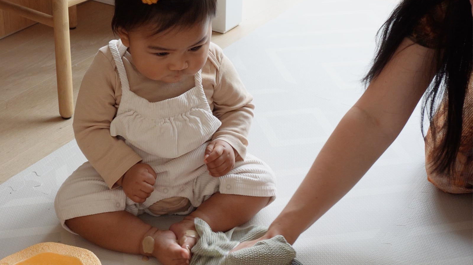 Mother easily cleaning an Eeveve EVA foam play mat with a soft cloth after her child’s spill during playtime.
