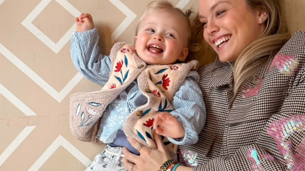 Mother and daughter lying on their backs together on an Eeveve play mat.
