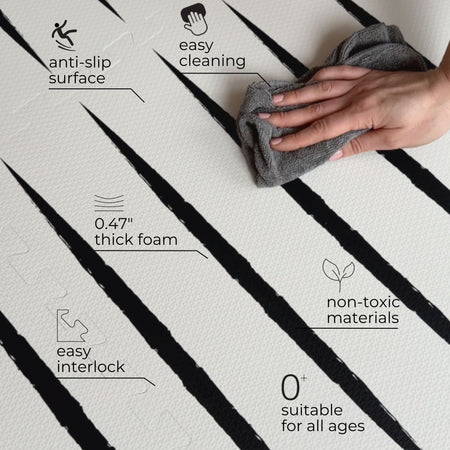 Hand wiping Lucio Ecru play mat showing features like anti-slip surface, soft EVA foam, and easy interlock for baby safety.