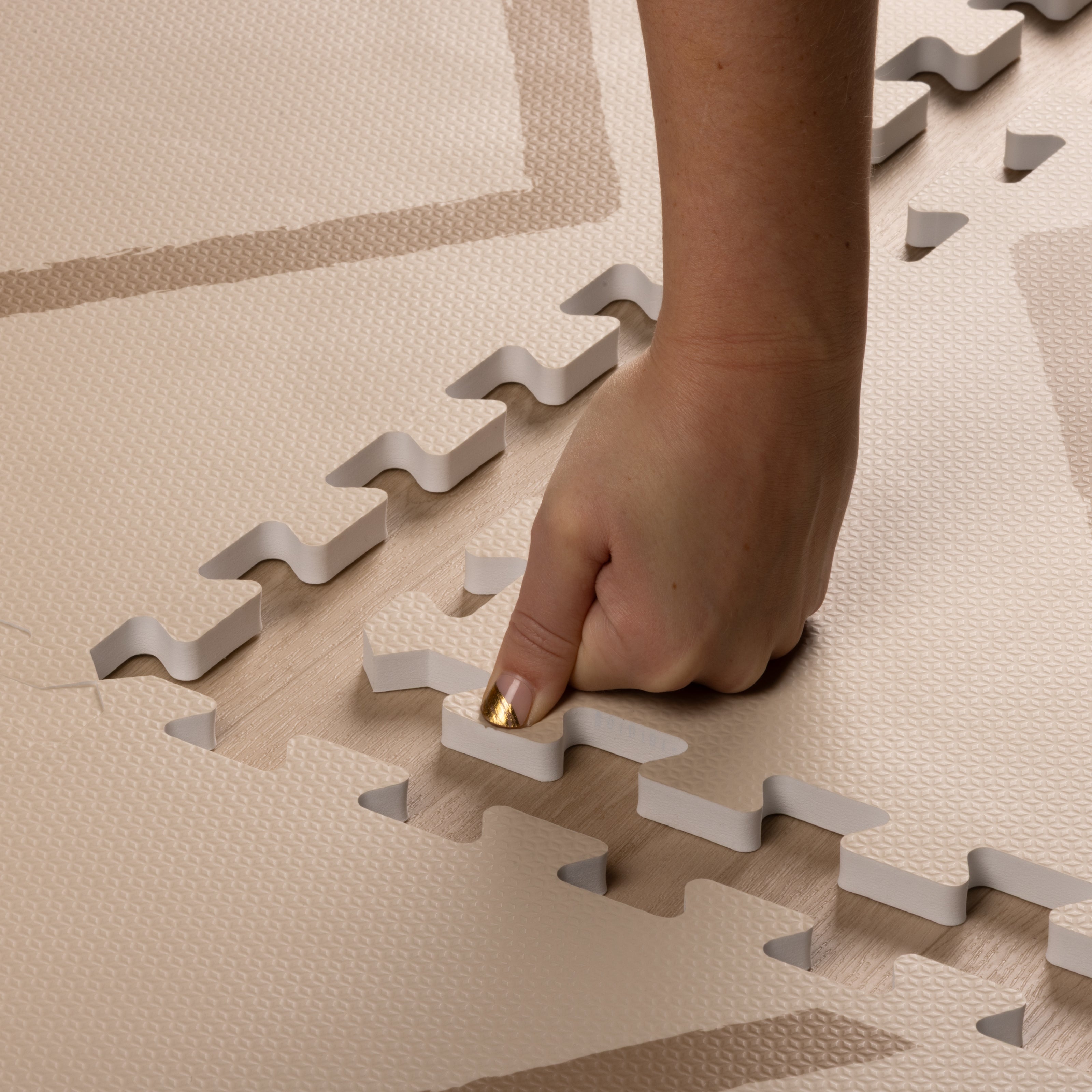 Hand pressing interlocking edge of Beni - Autumn Gold - Play Mat, showing soft, thick EVA foam texture and easy assembly design by Eeveve.