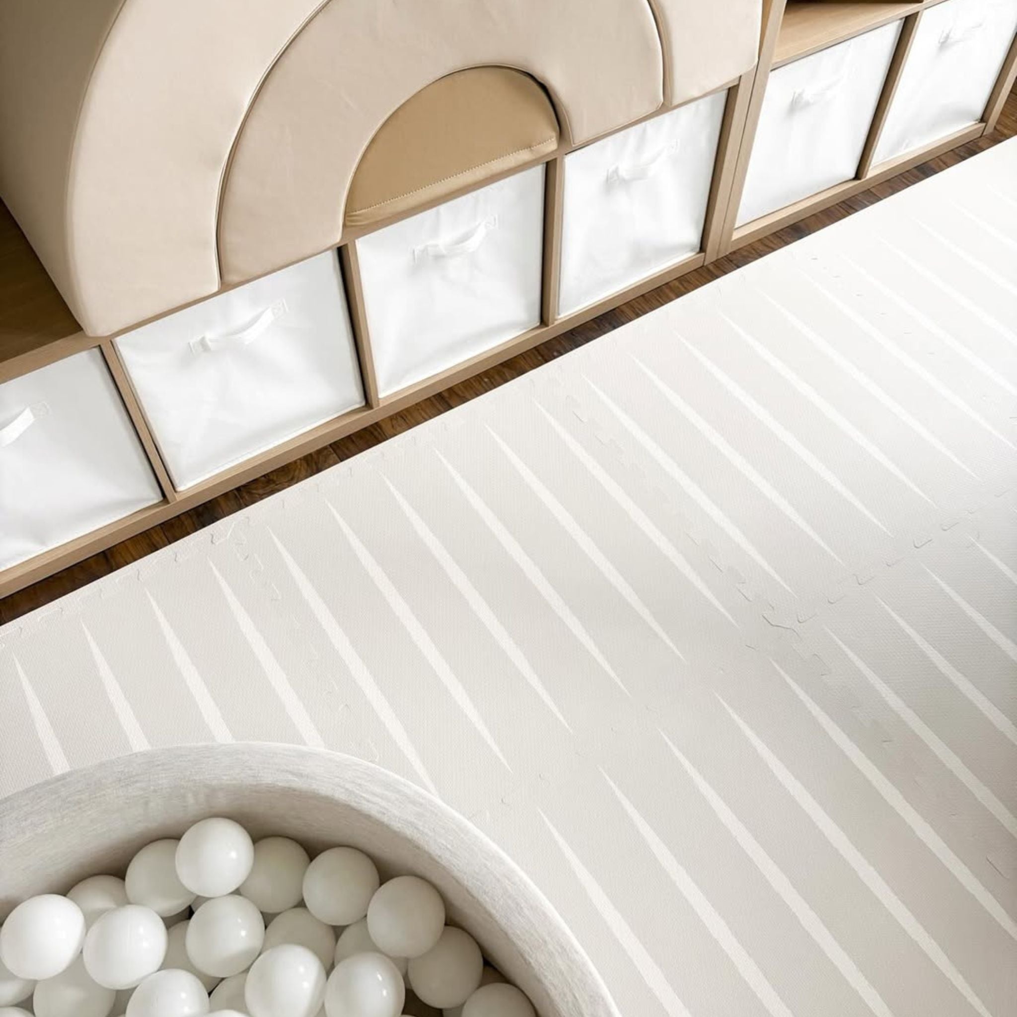 Detail of Lucio play mat in linen color by Eeveve next to a ball pit. Soft EVA foam surface perfect for baby playtime.