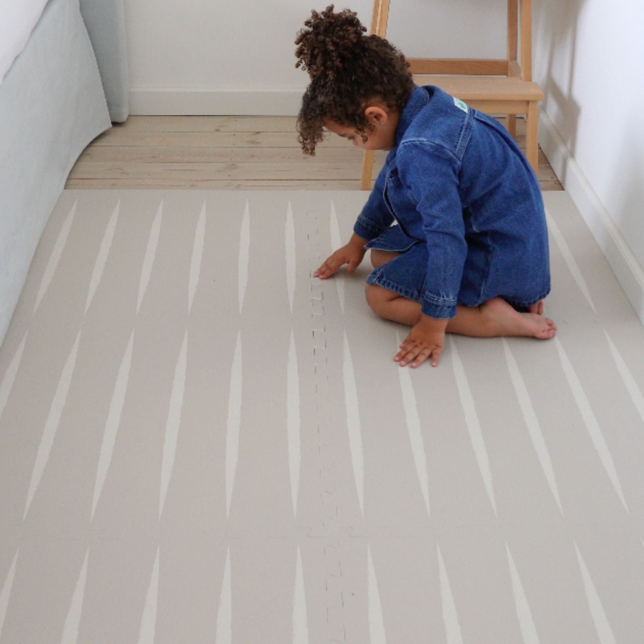 Child assembling the Lucio linen play mat by Eeveve. Safe and stylish EVA foam mat ideal for toddler play areas.