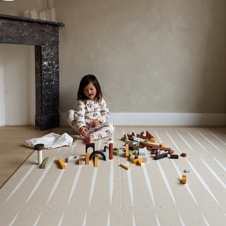 Child playing with wooden toys on Lucio Desert Sand Play Mat, designed for safe, stylish play in modern interiors.