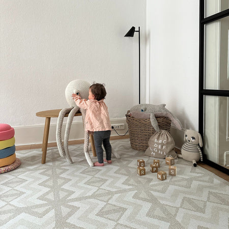 Baby playing on Kilim Feather Gray Play Mat in a modern nursery. Safe, stylish EVA foam mat perfect for early development and play activities.
