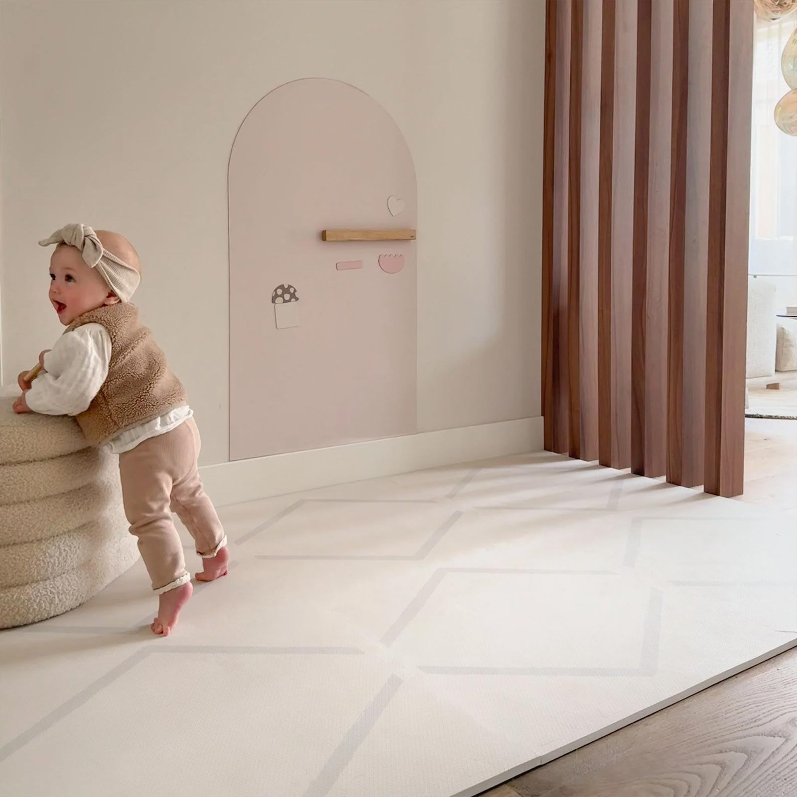 Baby standing and exploring on an Eeveve EVA foam play mat in a bright, minimalist living space.