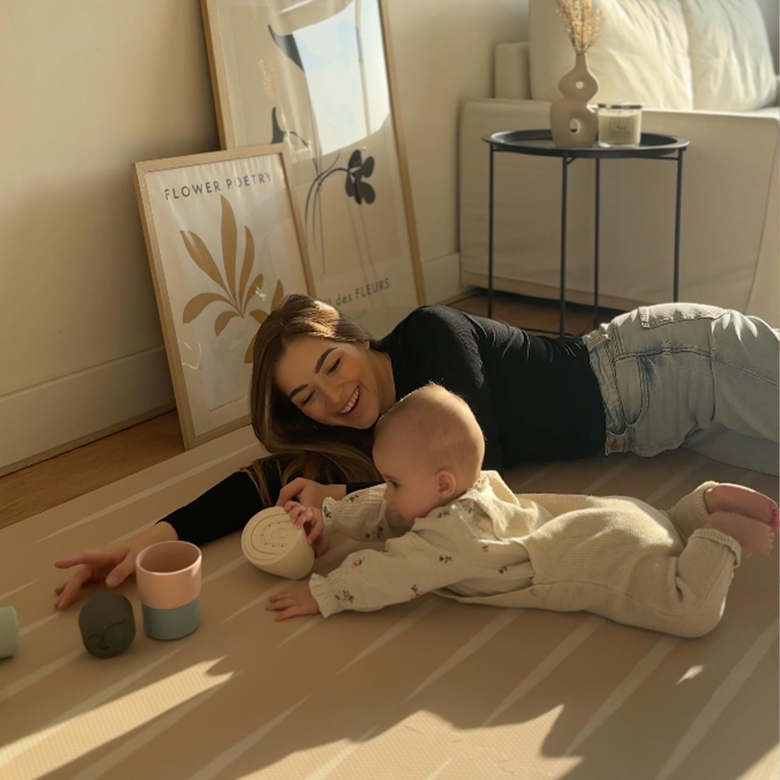 Mother lying on an Eeveve play mat with her baby during tummy time.