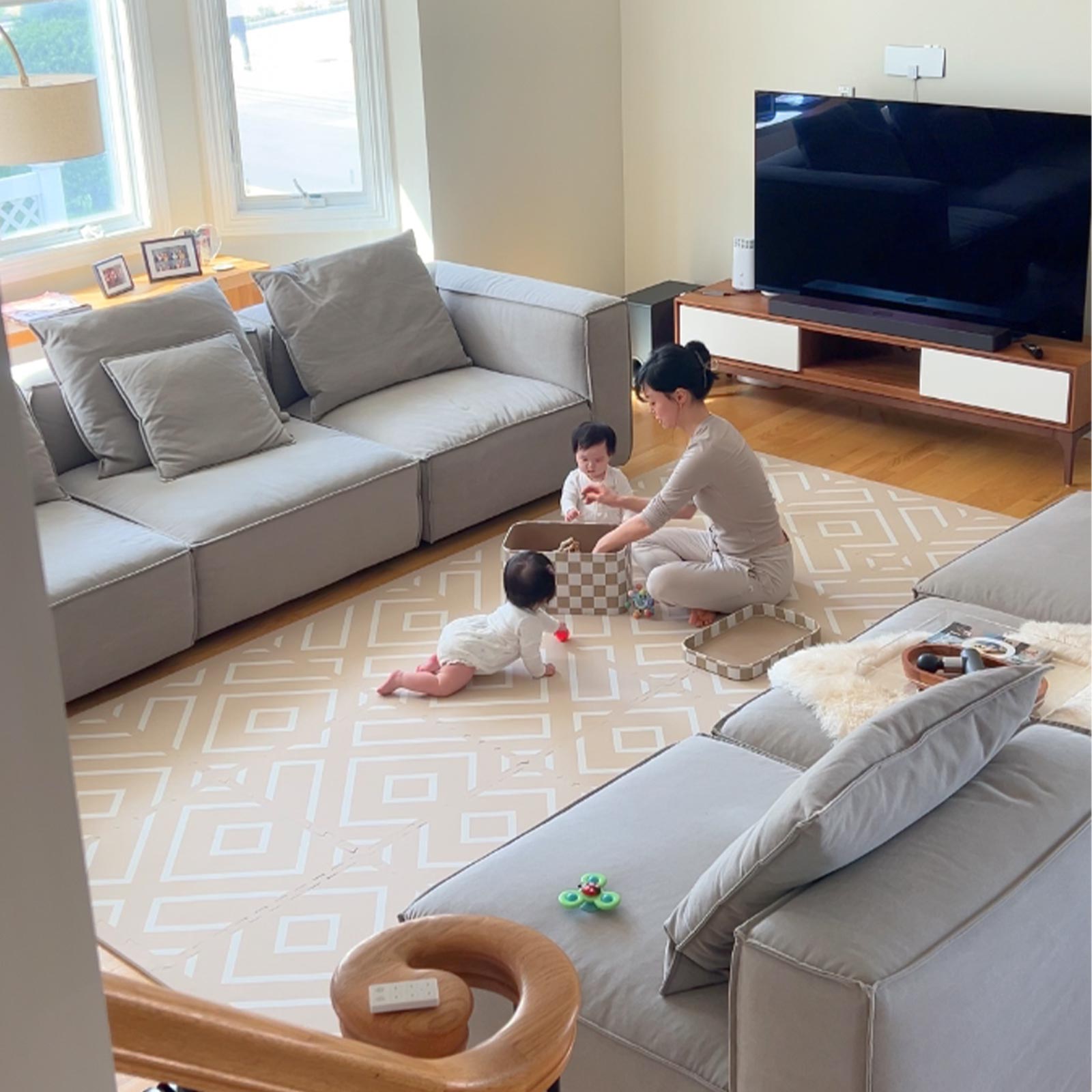 Mother playing with her two children on an Eeveve play mat in the living room.