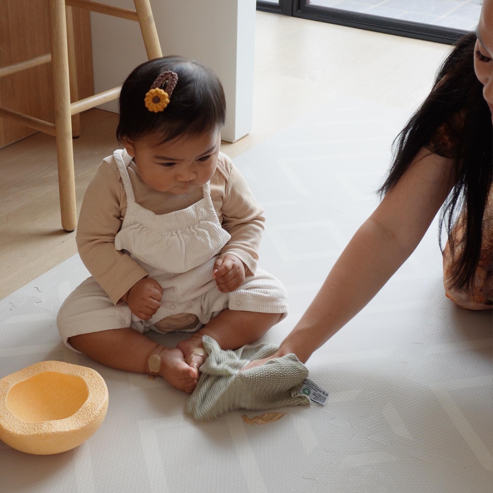 Mother easily cleaning an Eeveve EVA foam play mat with a soft cloth after her child’s spill during playtime.