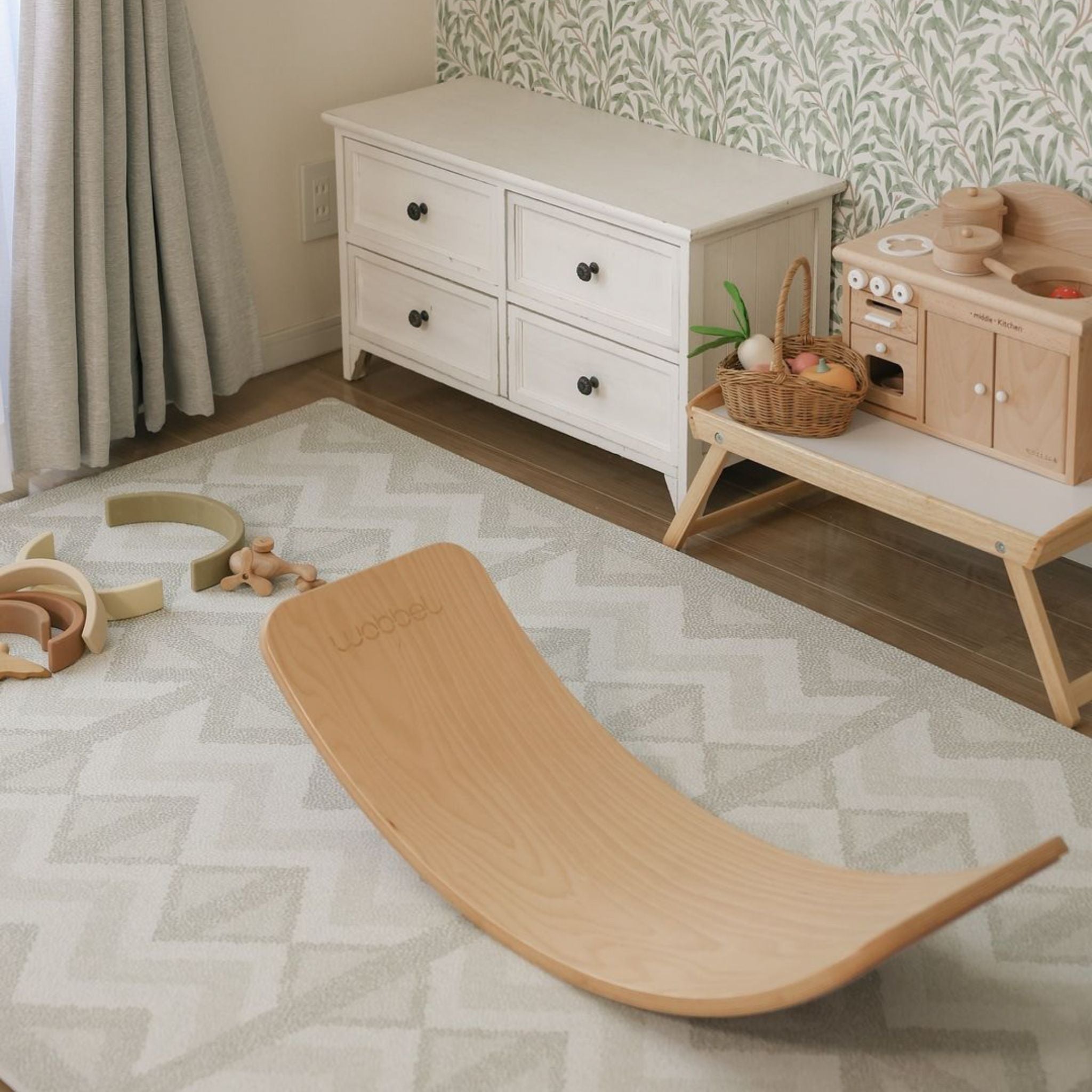 A patterned foam play mat laid across a living room floor in front of furniture, filling most of the open space