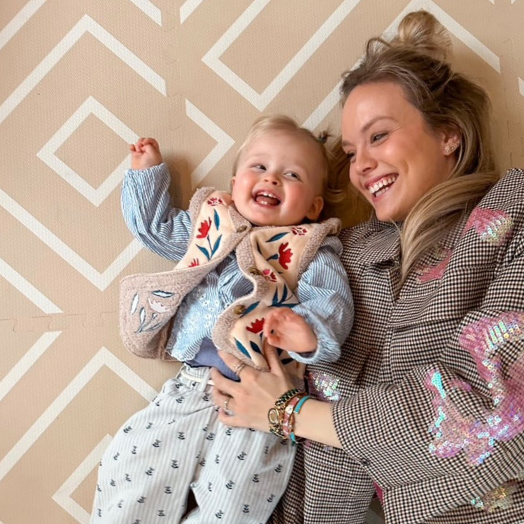 Mother and daughter lying on their backs together on an Eeveve play mat.