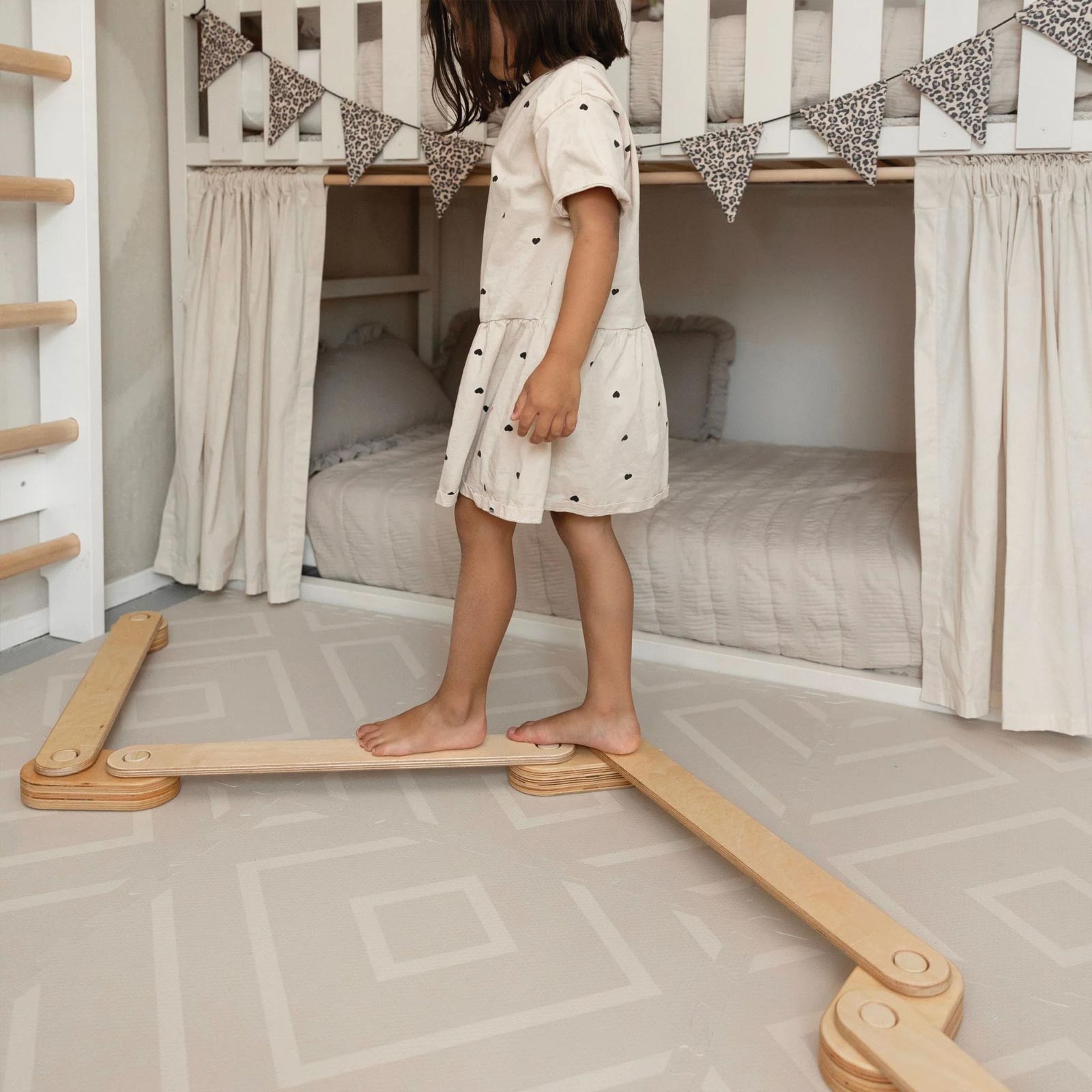 Child walking on a wooden balance board placed on an Eeveve play mat.