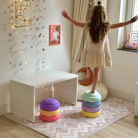 Child balancing on colorful cushions atop Eeveve Kilim Soft Clay play mat. Safe and stylish EVA foam mat for toddler activities.