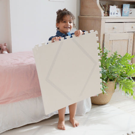 Child holding a Beni Cashmere play mat tile by Eeveve, a EVA foam mat with a minimalist diamond print, ideal for baby play areas.