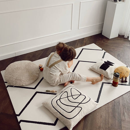 Two young children sitting on Eeveve Beni - Ecru play mat with cushions and toys, enjoying a cozy and safe playtime environment.