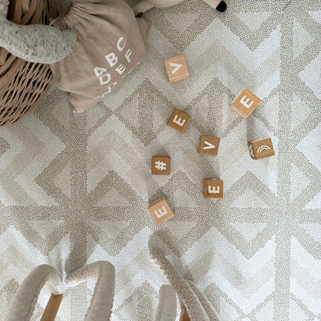 Wooden toys on Kilim Feather Gray Play Mat by Eeveve. Soft, textured EVA foam surface with modern print for safe baby playtime.